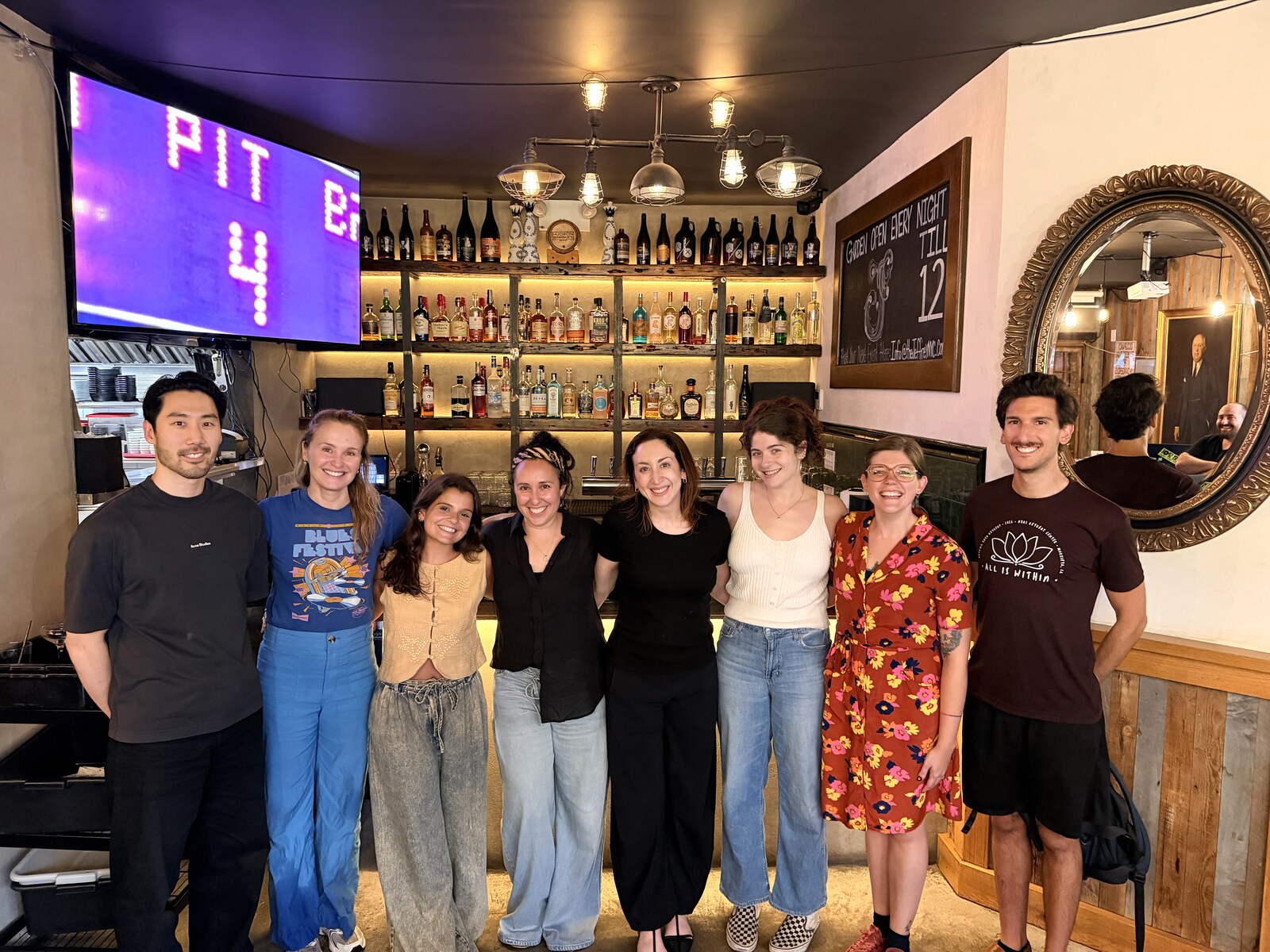 Eight KFT tutors standing together at a bar during a tutor happy hour.